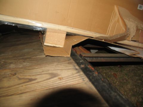 1988 Ford C-350 (Centurion Conversions) - Cardboard boxes and wooden planks are piled on a wooden floor, obscuring the ground below.