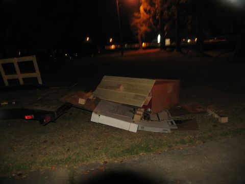 1988 Ford C-350 (Centurion Conversions) - A trailer is loaded with construction debris and materials, including wooden planks and cardboard boxes, at night.