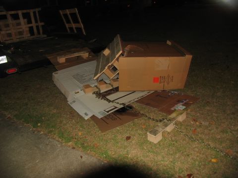 1988 Ford C-350 (Centurion Conversions) - Debris including cardboard boxes and wooden pallets is piled on the grass.