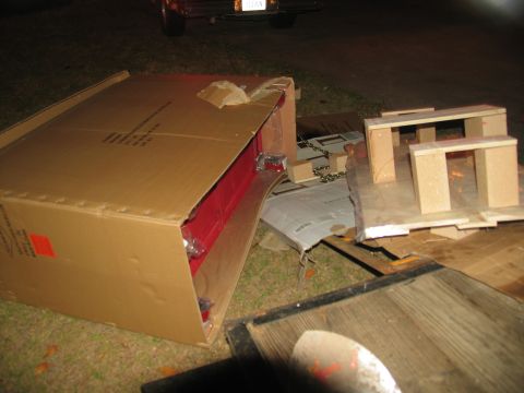 1988 Ford C-350 (Centurion Conversions) - A red toolbox is partially visible inside a damaged cardboard box, surrounded by debris and a vehicle in the background.