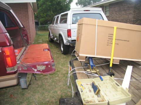 1988 Ford C-350 (Centurion Conversions) - White Ford Bronco and maroon van, with a large box being loaded onto a trailer.