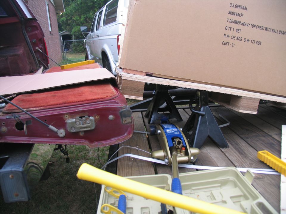 Silver van with a red tailgate in the foreground, parked on a wooden deck
