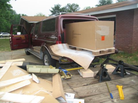 1988 Ford C-350 (Centurion Conversions) - A maroon SUV is parked with its doors and tailgate open, loaded with a large cardboard box on a pallet.