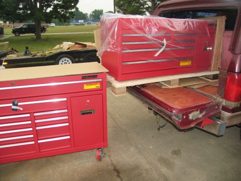 1988 Ford C-350 (Centurion Conversions) - A red toolbox is loaded onto a pallet in the bed of a pickup truck, with another toolbox nearby.