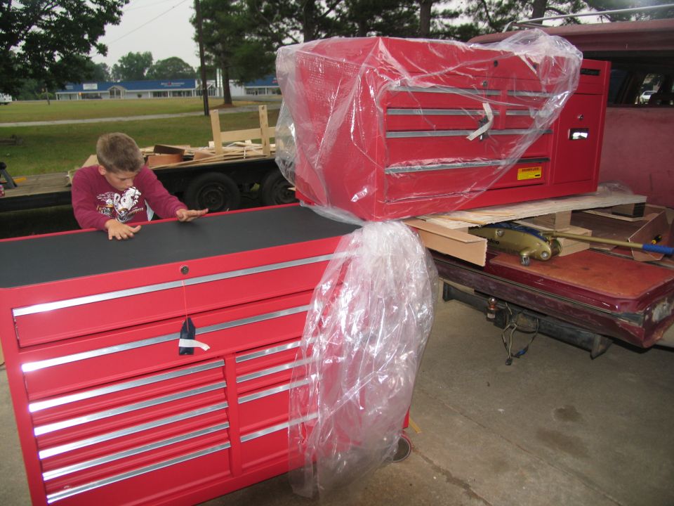 Red toolboxes on a trailer with a boy looking at them