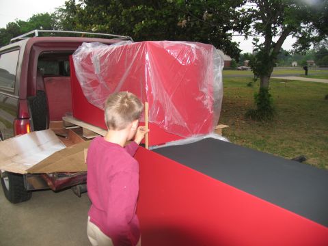 1988 Ford C-350 (Centurion Conversions) - A person helps load a large red toolbox into the rear of a van.