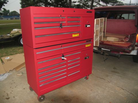 1988 Ford C-350 (Centurion Conversions) - A large red toolbox sits on a driveway next to a red pickup truck with its tailgate down.