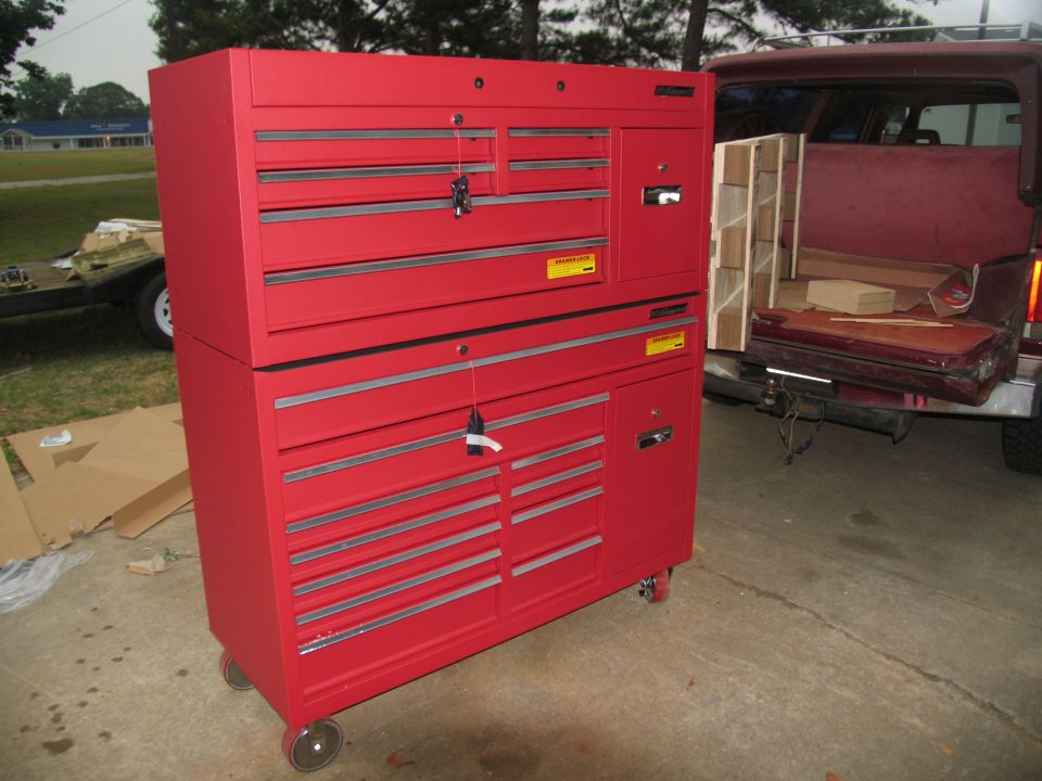 Red rolling tool chest on driveway next to maroon pickup with tailgate down