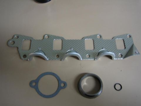 1987 Suzuki Samurai - A set of exhaust manifold gaskets, a metal ring, and an O-ring are laid out on a neutral surface.