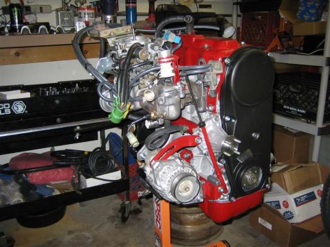 1987 Suzuki Samurai - Engine assembly on a stand, likely for a Suzuki Samurai build, with garage clutter visible.