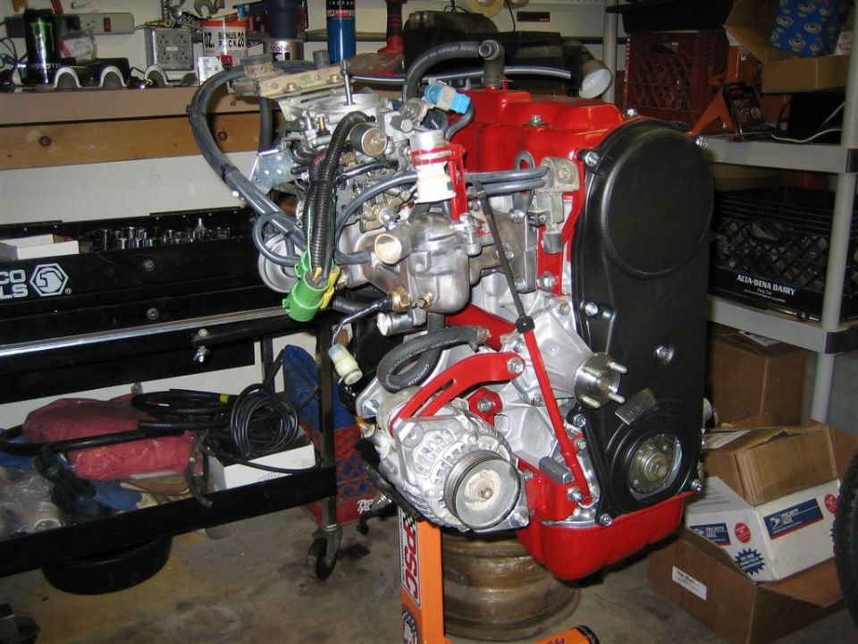 Engine assembly on an orange stand in a garage, with tools and boxes in the background