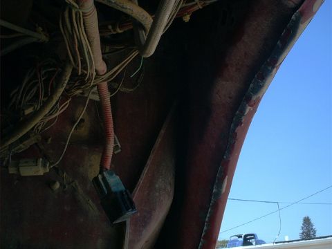 1986 Ford Bronco - Close-up view of the wiring harness in the engine bay, showing a red conduit and a black connector.