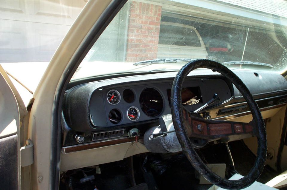 Tan dashboard and steering wheel of a 1978 Dodge Power Ram truck with aftermarket gauges