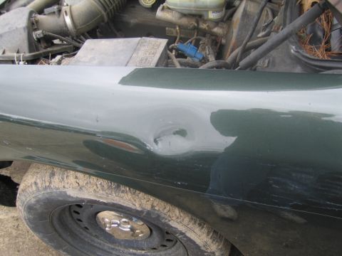 1991 Ford LTD Crown Victoria - Side view of a dented 1991 Ford Crown Victoria LTD fender, with the engine bay visible.