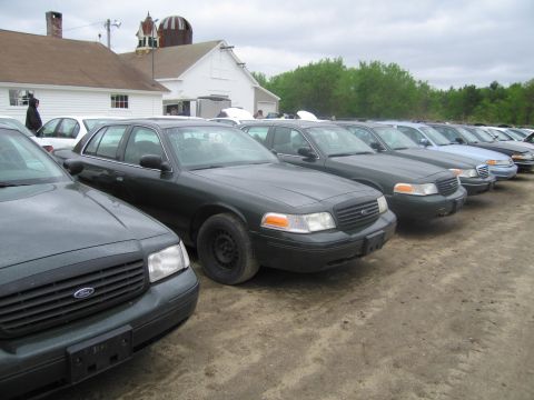 1991 Ford LTD Crown Victoria - A line of Ford Crown Victoria police cars are parked outside a building.