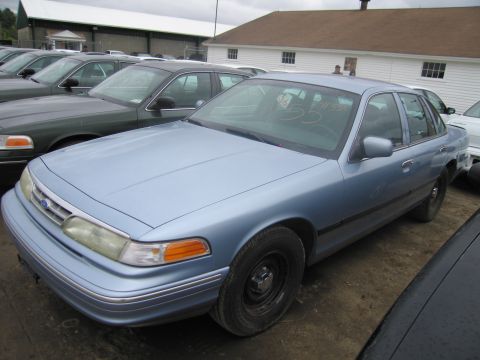 1991 Ford LTD Crown Victoria - A light blue sedan is parked in a lot with other vehicles, showing its front quarter profile.