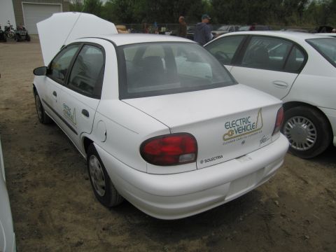 1991 Ford LTD Crown Victoria - A white electric vehicle is parked outdoors with its hood up, next to another white car.