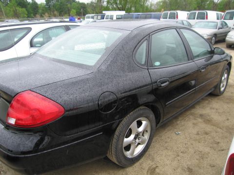 1991 Ford LTD Crown Victoria - A black sedan is viewed from the rear quarter angle in an outdoor lot with other vehicles present.