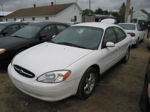 1991 Ford LTD Crown Victoria - A white sedan is parked in a lot with other vehicles under an overcast sky.