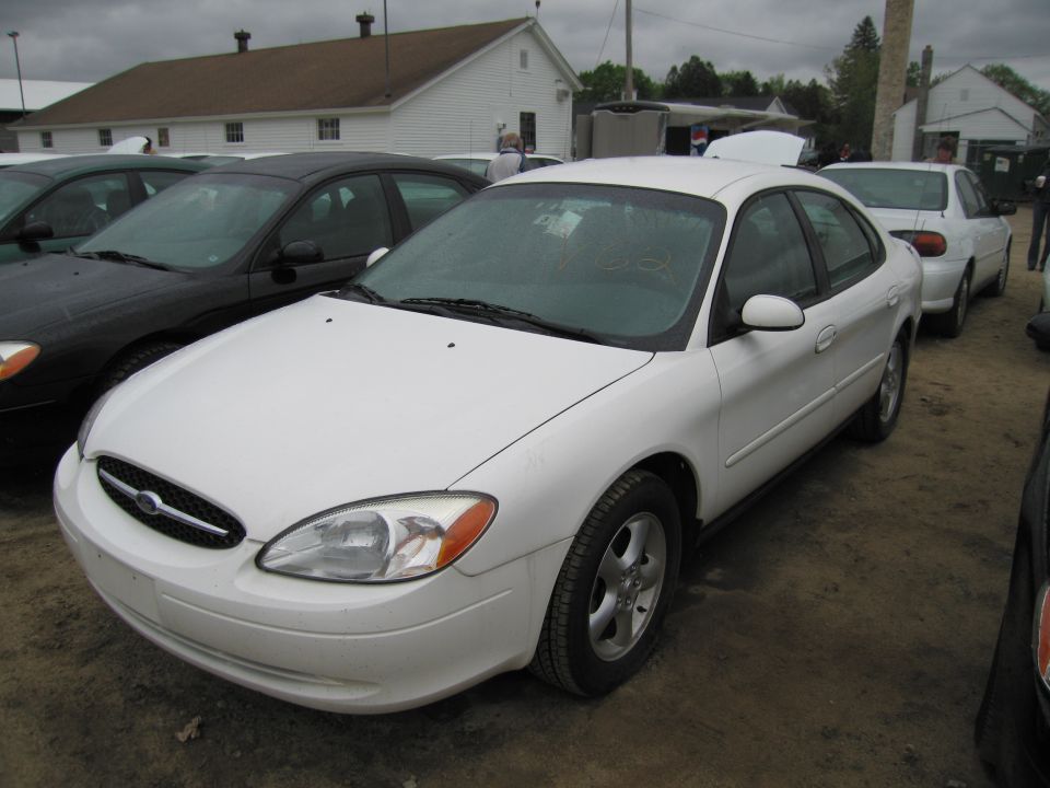 White sedan parked outdoors, front quarter view. Some dirt on windshield