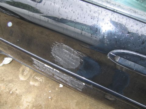 1991 Ford LTD Crown Victoria - Close-up of a damaged car door, showing scuffs and paint imperfections.