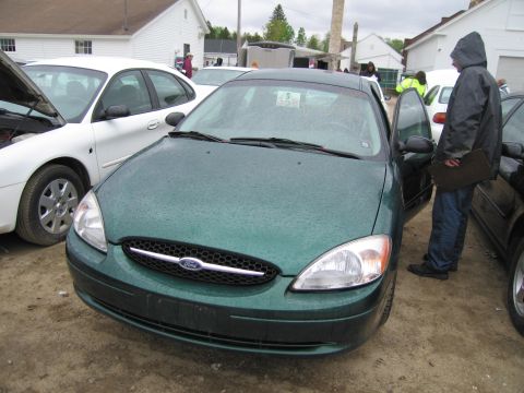 1991 Ford LTD Crown Victoria - Front view of a green Ford Taurus with the driver's door open.
