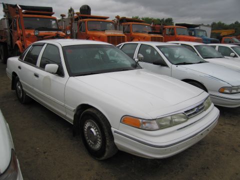 1991 Ford LTD Crown Victoria - A white 1991 Ford Crown Victoria LTD sedan is parked in a lot with other vehicles.