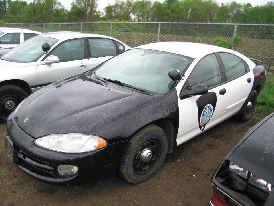Police car with black front and white rear, number 05 on fender. Another car is parked next to it