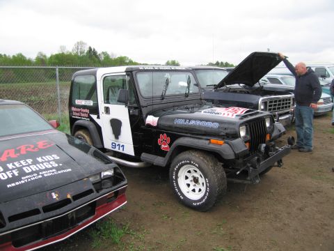 1991 Ford LTD Crown Victoria - A black and white Jeep Wrangler is parked next to a black car with red trim.