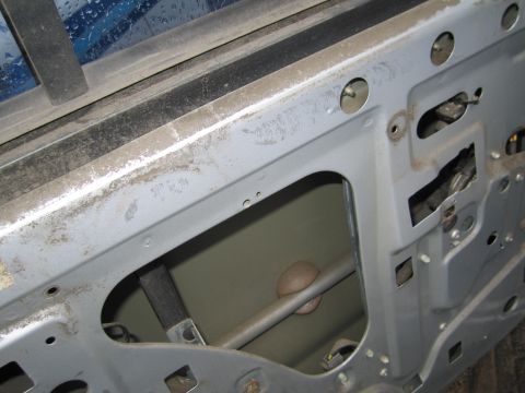 1991 Ford LTD Crown Victoria - Close-up view of the internal workings of a car door, revealing the window regulator assembly.