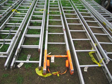 1991 Ford LTD Crown Victoria - Several extension ladders are stored outdoors on a grassy area, with some marked with caution tape and numbered tags.