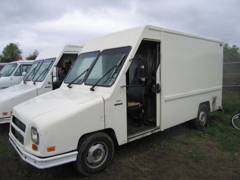 1991 Ford LTD Crown Victoria - Several white step vans are parked in a lot under an overcast sky. The front van has its driver's side door open.