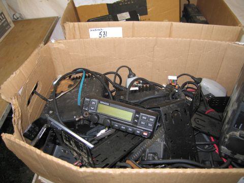 1991 Ford LTD Crown Victoria - A collection of radio equipment is piled inside a cardboard box, with some items visible in other boxes behind it.