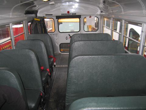 1991 Ford LTD Crown Victoria - The interior of a school bus shows rows of seats and an emergency exit door.