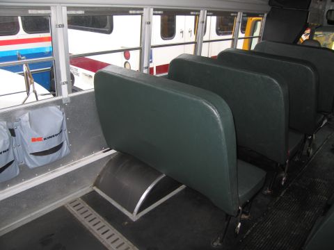 1991 Ford LTD Crown Victoria - View from inside a bus, looking past rows of seats towards windows that reveal other buses outside.
