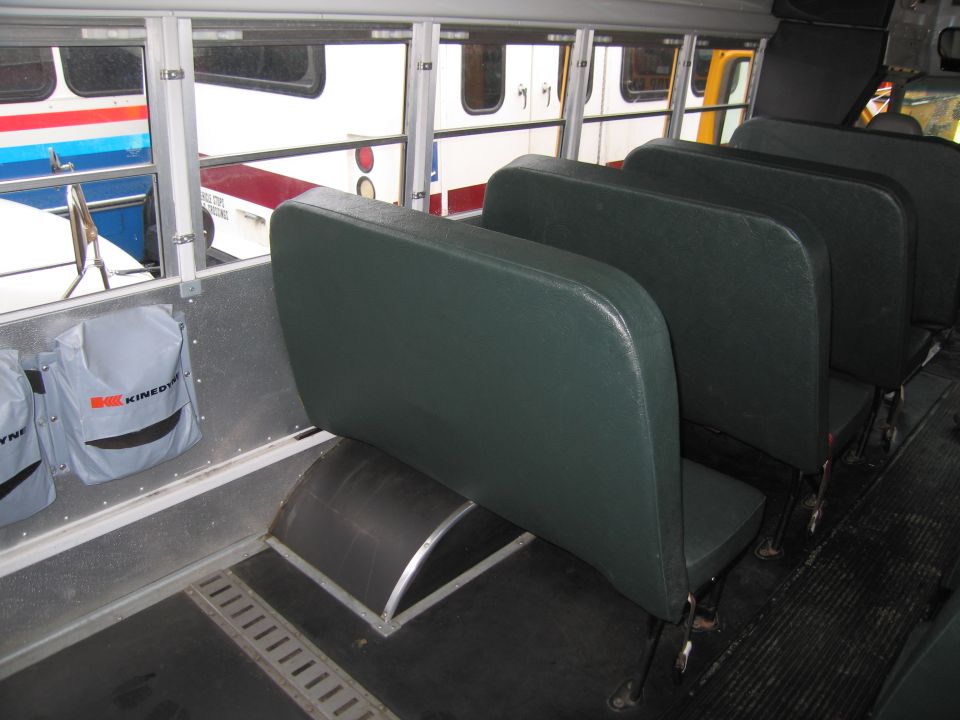Interior of a bus showing rows of green seats and windows looking out onto other buses