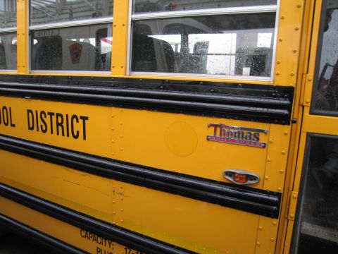 1991 Ford LTD Crown Victoria - A yellow school bus with black trim and windows is shown from the side, with text indicating it belongs to a school district.