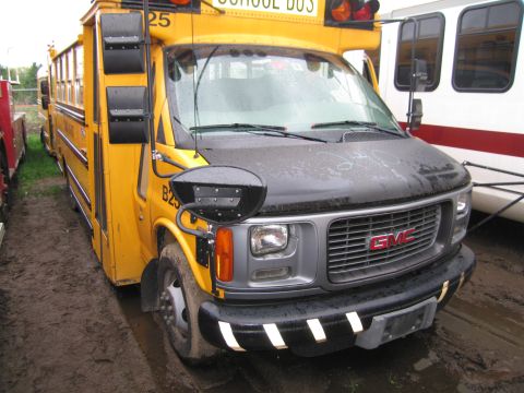 1991 Ford LTD Crown Victoria - A yellow school bus is parked next to a white bus with a red stripe.