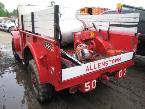 1991 Ford LTD Crown Victoria - A red fire truck with "ALLENSTOWN 50 02" written on its tailgate is parked in muddy terrain.