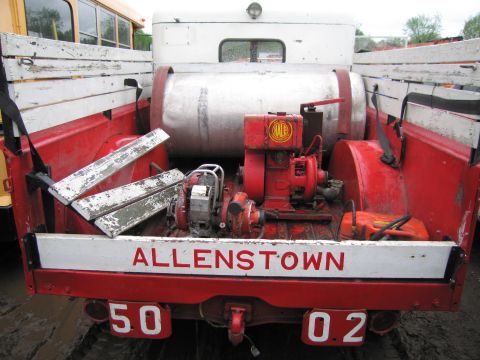 1991 Ford LTD Crown Victoria - Rear view of a red truck bed containing a large silver tank and two red engines, with "ALLENTOWN 50 02" painted on the tailgate.
