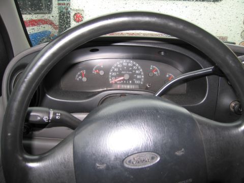 1991 Ford LTD Crown Victoria - Interior view of a Ford vehicle's dashboard and steering wheel, with a truck seen through the rain-streaked windshield.