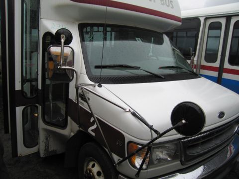 1991 Ford LTD Crown Victoria - A white van with a maroon stripe and the number 2 is parked next to another bus.