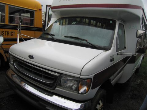 1991 Ford LTD Crown Victoria - A white Ford E-Series RV is parked next to a yellow school bus, with the front of the RV facing the camera.