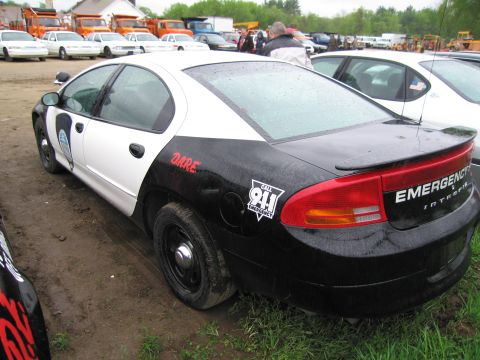 1991 Ford LTD Crown Victoria - This police car, marked with DARE and 911 Emergency decals, is seen from the rear in a lot with other vehicles.