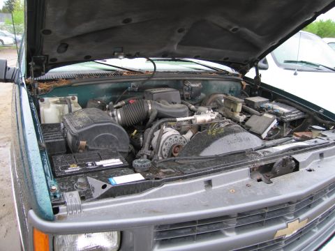 1991 Ford LTD Crown Victoria - The engine bay of a green truck is open, revealing the engine components and battery.
