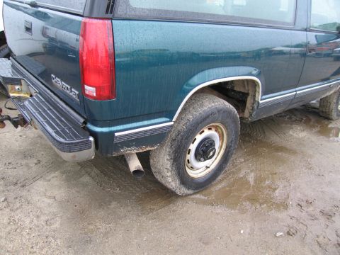 1991 Ford LTD Crown Victoria - Rear view of a teal Chevrolet Suburban with visible "CHEVROLET" badging on the tailgate.