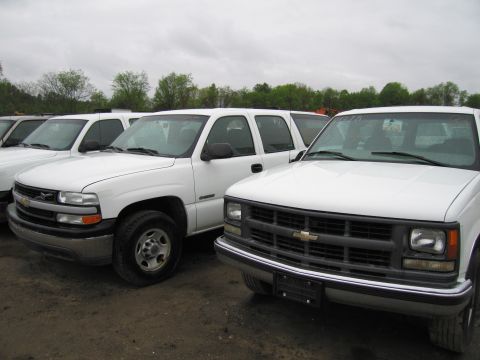 1991 Ford LTD Crown Victoria - Multiple white Chevrolet pickup trucks are parked in an outdoor lot under an overcast sky.