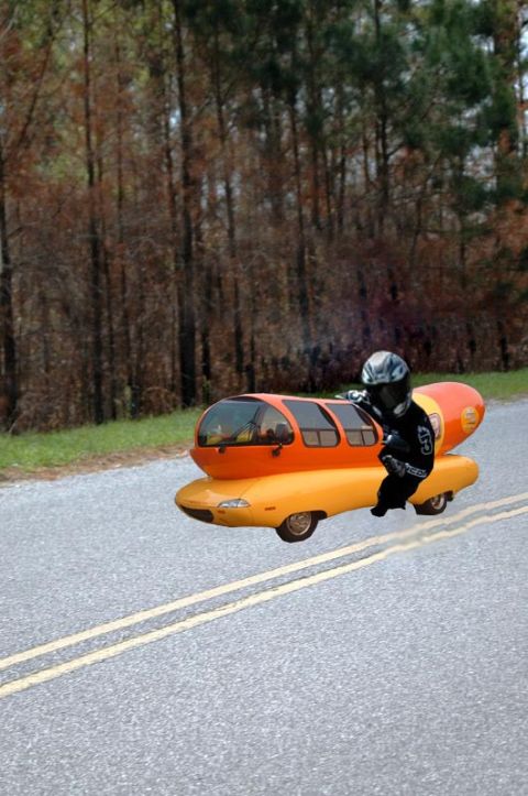 1997 Ford Probe - A person in motorcycle gear appears to be riding the iconic Oscar Mayer Wienermobile down a two-lane road.