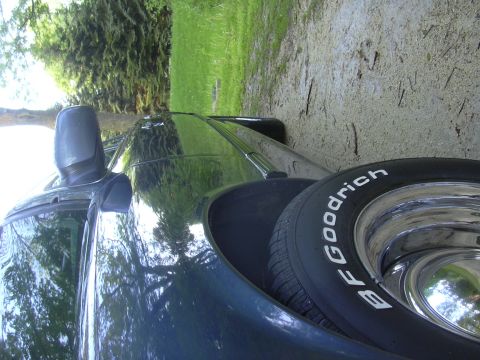 1996 Ford Crown Victoria - A dark sedan with BFGoodrich tires and chrome wheels is parked outdoors.
