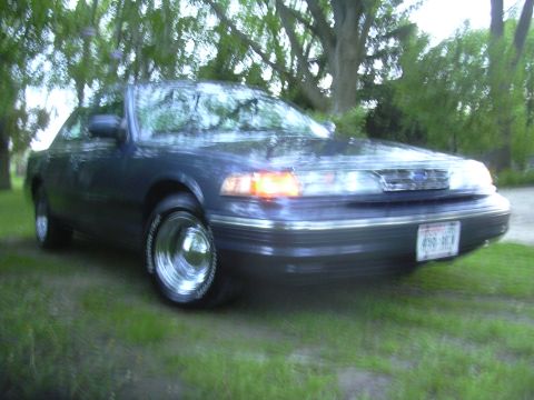 1996 Ford Crown Victoria - A dark blue 1995 Ford Crown Victoria is parked on a grassy area with trees in the background.